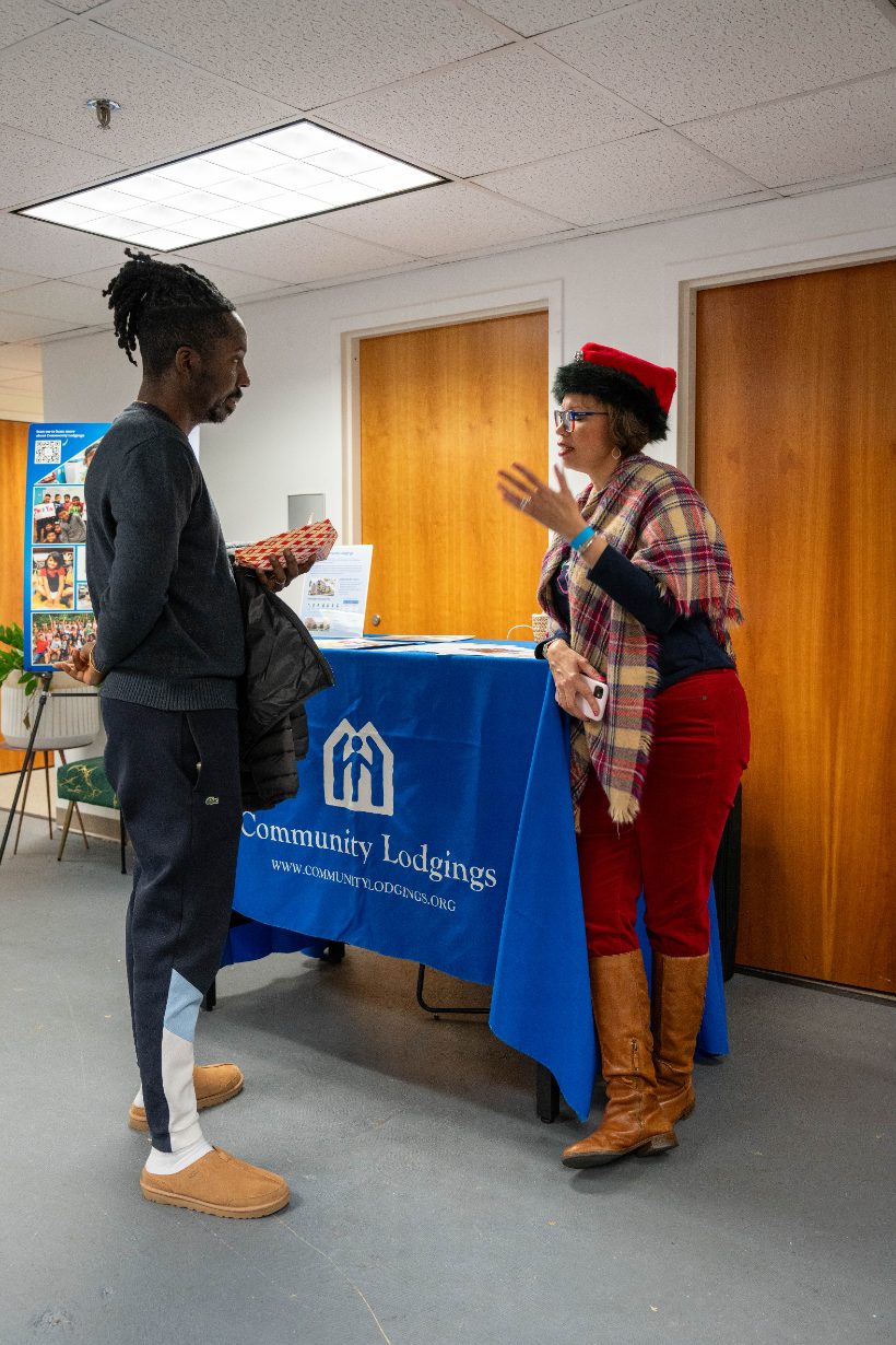 A visitor talking with a volunteer at the Community Lodgings table