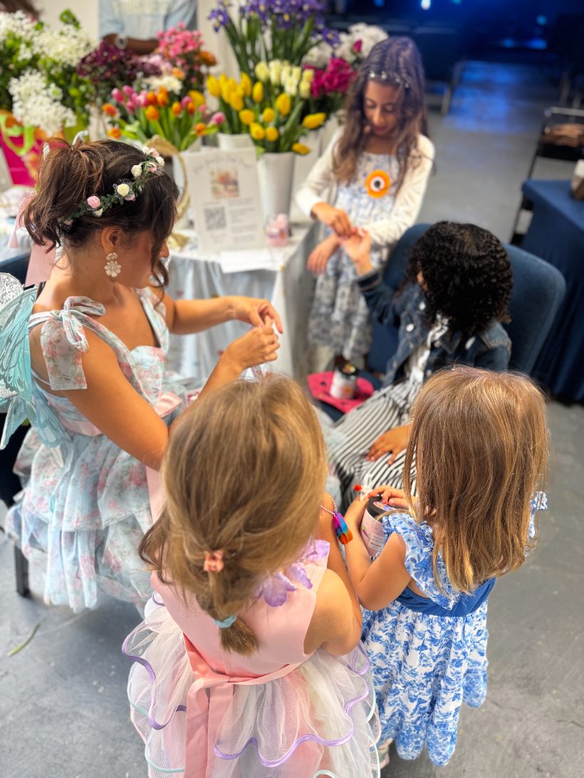 Children in fairy wings making crafts beside buckets of spring flowers